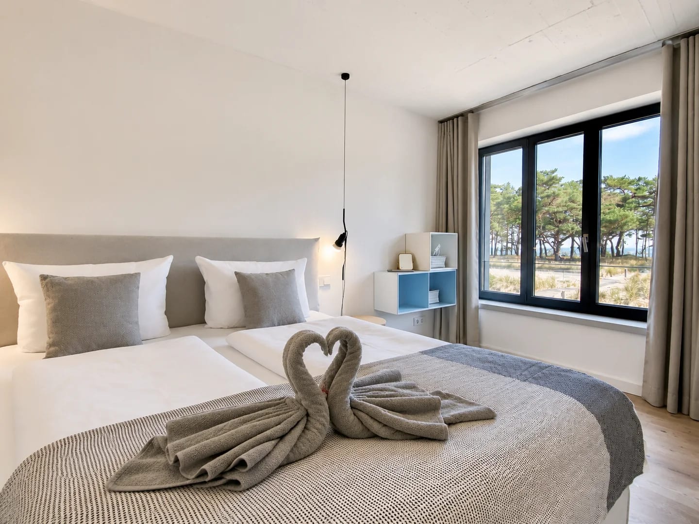 Nachher: Schlafzimmer mit Meerblick, ruhigerem Licht und dekorativen Handtuch-Schwänen auf dem Bett