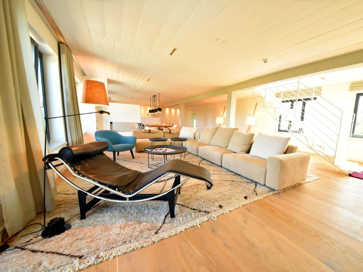 Vorher: Penthouse-Wohnzimmer mit Sofa, Liege, Treppe und warmem Licht